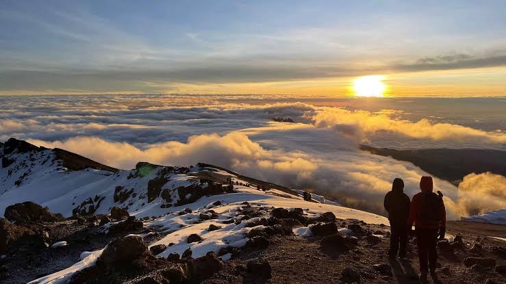 Climbers watching sunrise from the summit ridge of Kilimanjaro